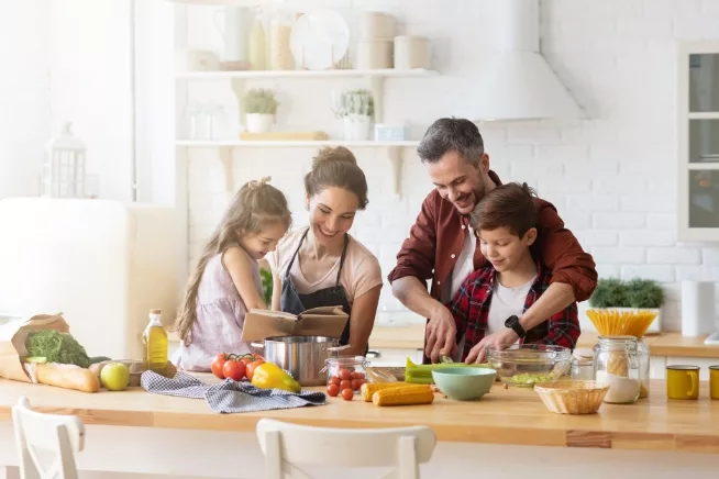 A warm and inviting scene of a family together in a well-lit kitchen, actively engaged in cooking dinner, highlighting the collaborative effort, the array of ingredients, and the heart of the home atmosphere.